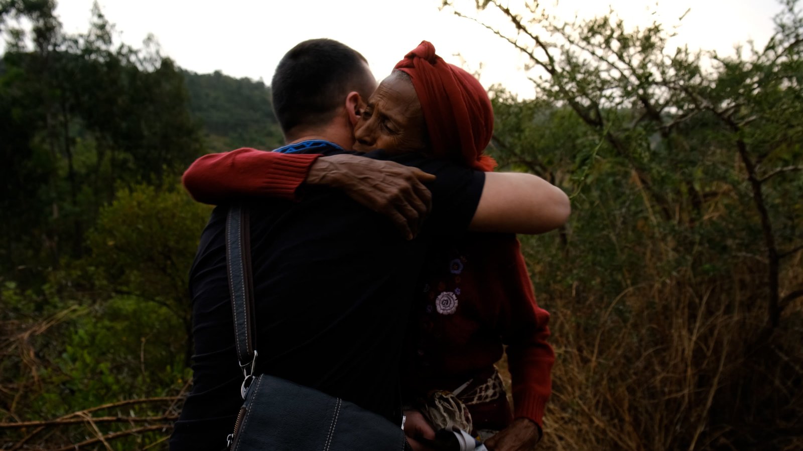 A team member embracing an older woman outdoors.